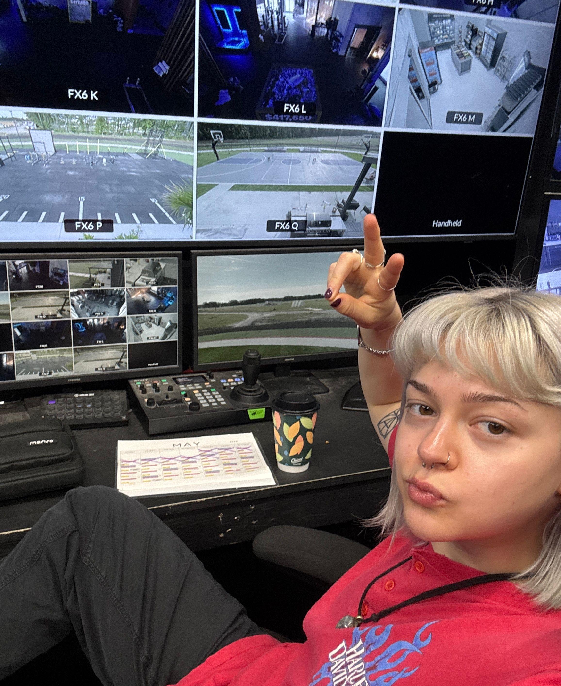 Emmy sits in a control room, watching a monitor with a feed from several live cameras